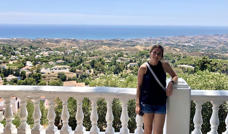 Christina standing at a balcony overlooking the Mediterranean